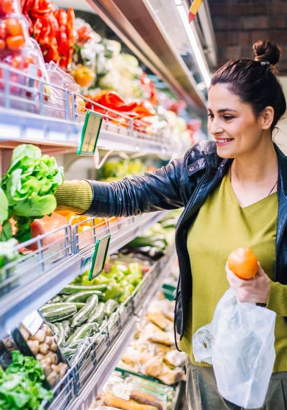 Woman on the produce section of the grocery store. hacks to save money on groceries.