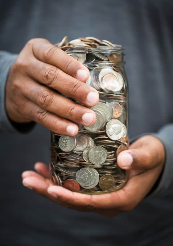 Hands holding a jar with coins.