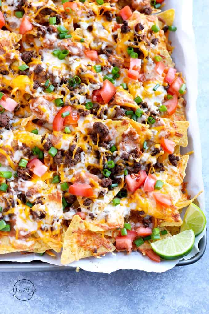 beef nachos with cheese, black beans and red peppers in a sheet pan
