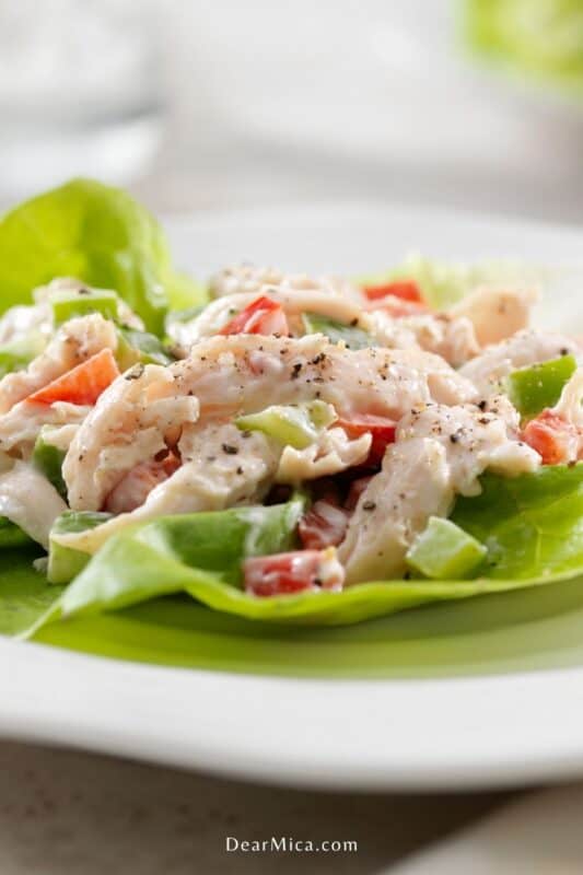 Top view of a creamy low carb chicken lettuce wrap with red and green peppers served on a white plate.