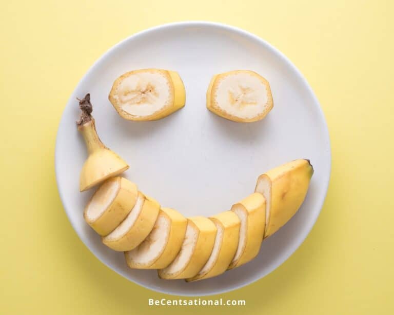 Top view of a sliced banana forming a happy smily face on a gray plate on a yellow background. Do Bananas Have Seeds.