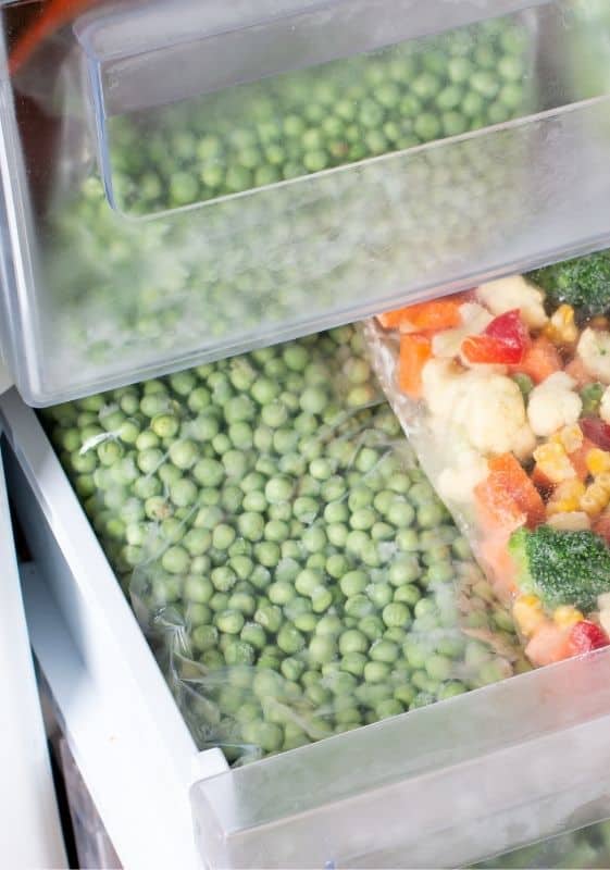 Frozen peas stored in the freezer in bags.