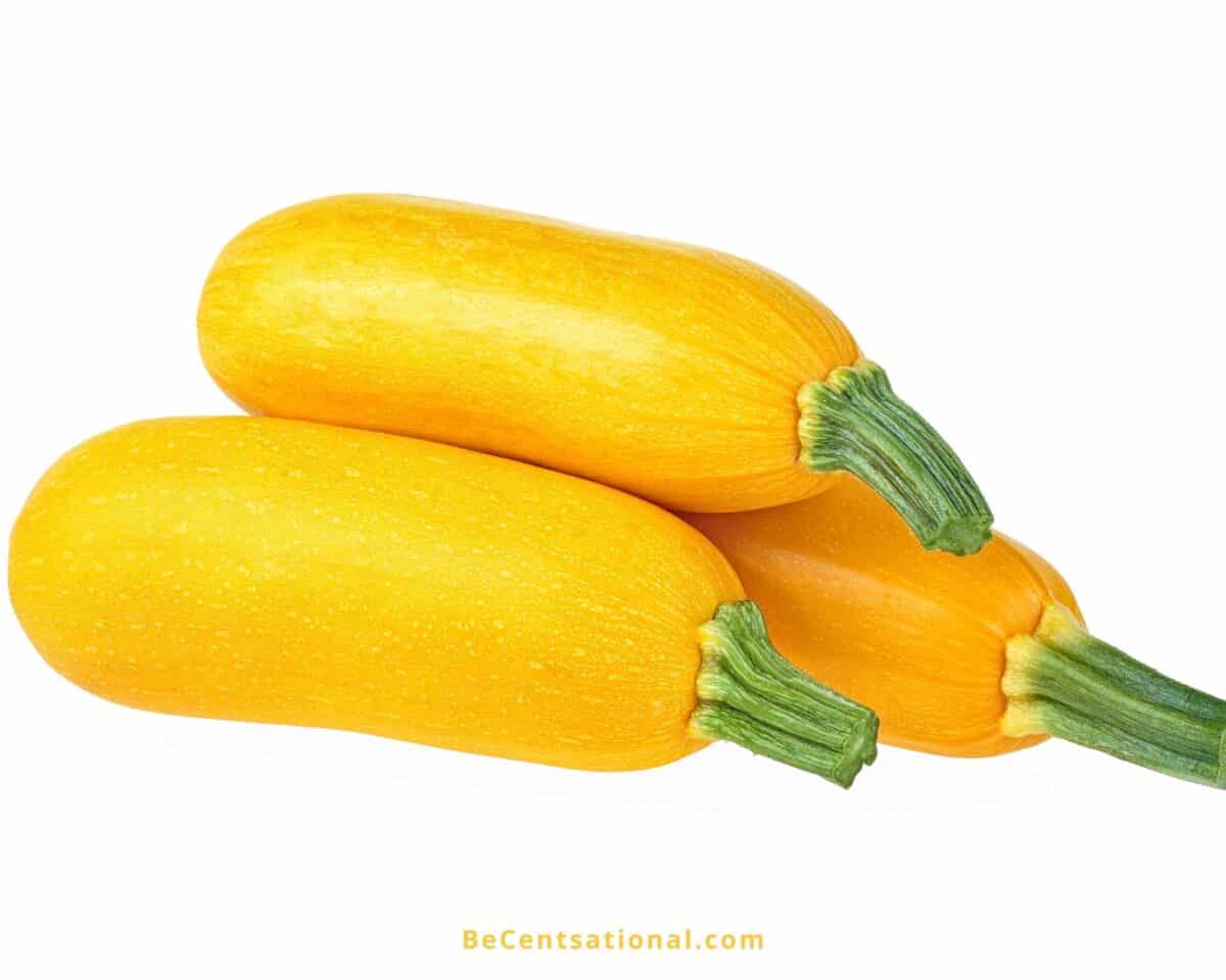 side view of 3 zucchinis on a white background. Foods that are yellow.