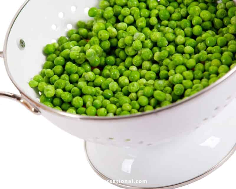 Frozen peas in white colander. How to Defrost Peas?
