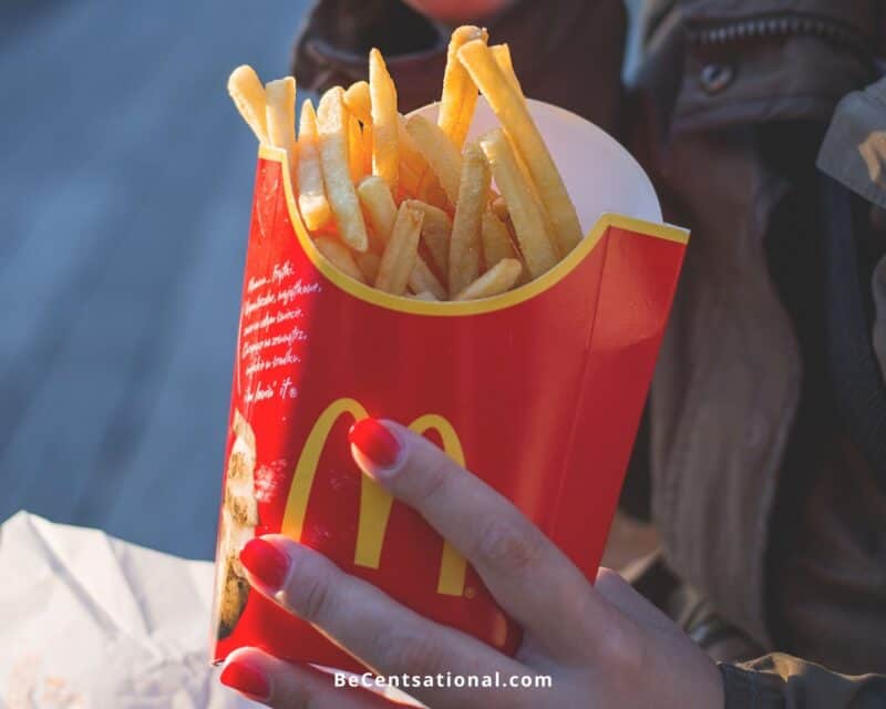 Side view of woman holding large McDonald's fries. How to Reheat McDonald's Fries