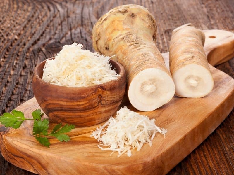 Fresh whole horseradish and grated horseradish in a bowl on a wood board. Is Horseradish a Radish?