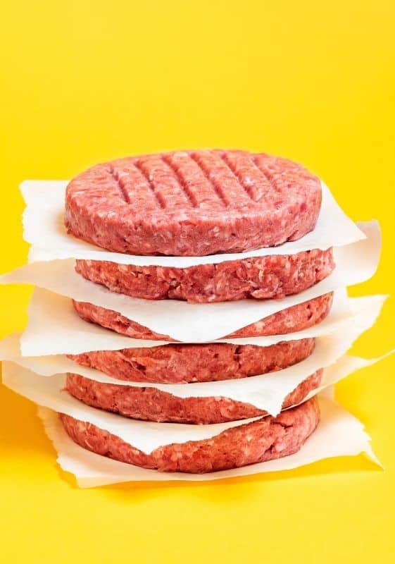 Side view of frozen burger patties stacked up.
