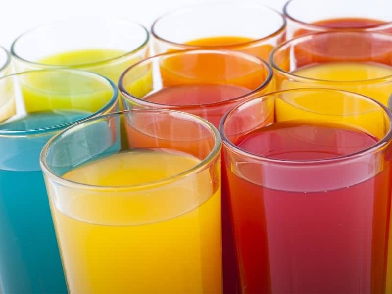 View of several glasses of kool-aid in different flavors and colors.