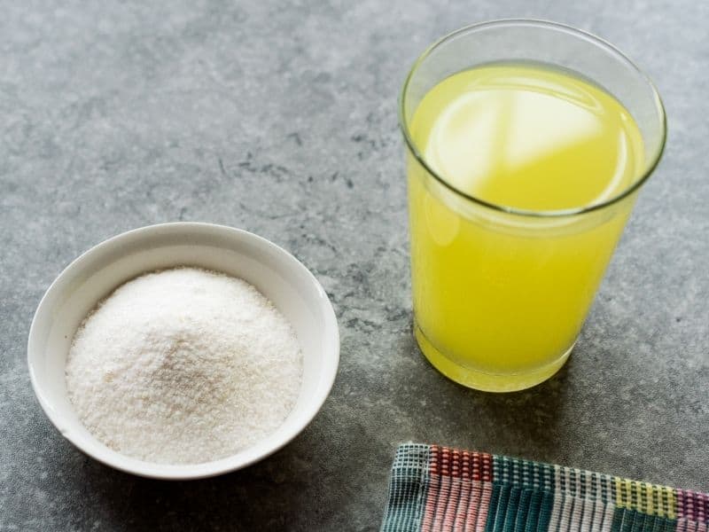Top view of a glass of mixed lemonade and powdered lemonade in a small bowl.