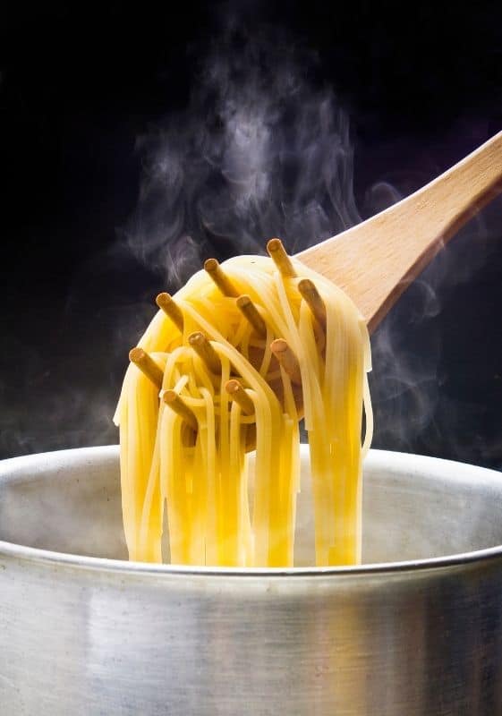 Stirring pasta so it does not stick and clump together.