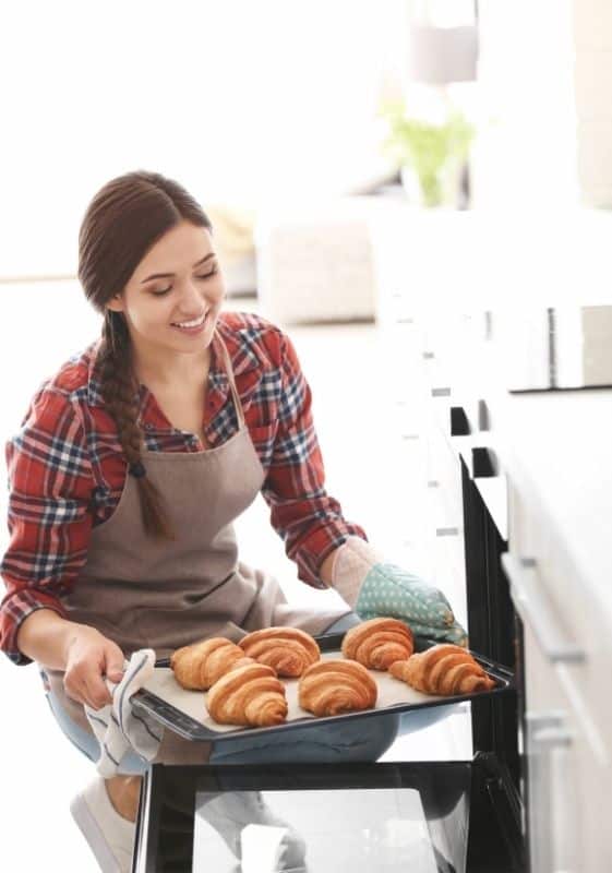 Woman takin out baked croissants from the oven. Can You Freeze Croissants?