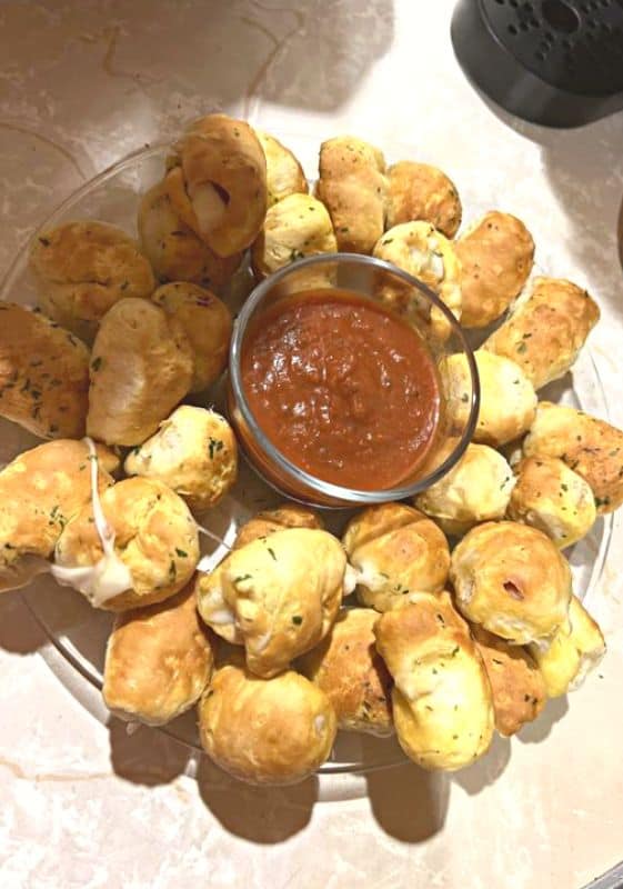 mini crescent rolls stuffed with mozzarella cheese fresh out of the oven with marinara dipping sauce.