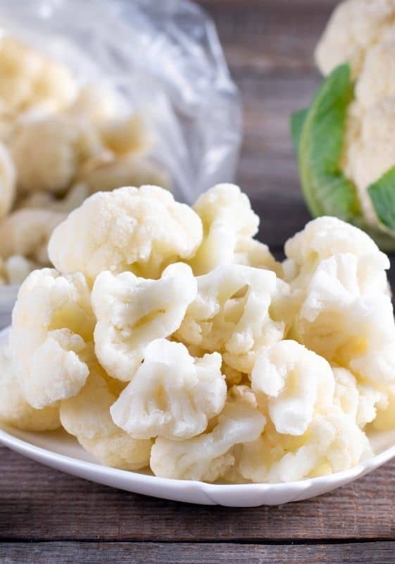 Steamed cauliflower without a steamer on a white plate.