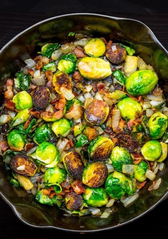 Sautéed Brussels Sprouts on a cast iron skillet with a black background.