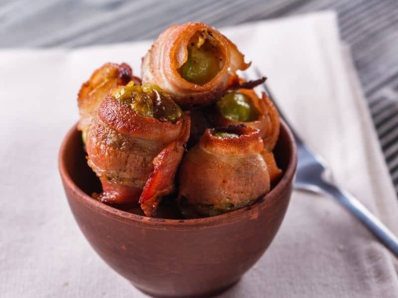 Side view of Wrapped Bacon Brussels Sprouts appetizers in a bowl.