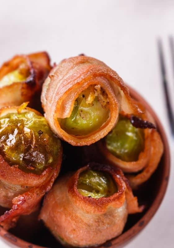 Closeup view of a bowl of Bacon wrapped Brussels Sprouts appetizers.
