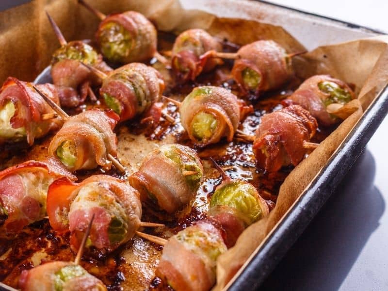 Baked tray of bacon wrapped brussels sprouts.
