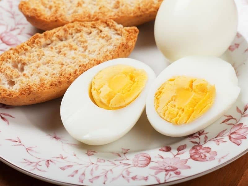two hard boiled eggs cooked in the air fryer served with two slices of toast on a red and white plate.