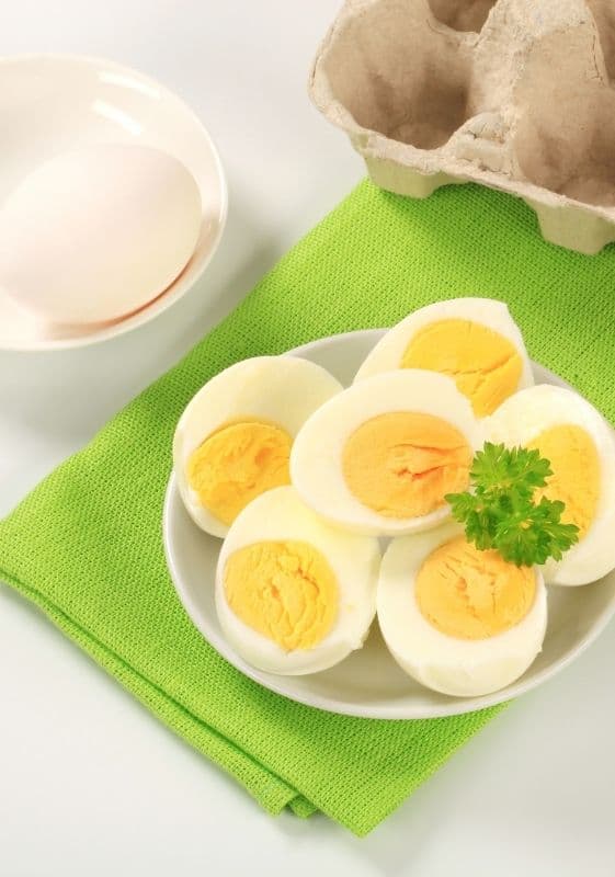 Plate full of boiled eggs cut in half on a green napkin.