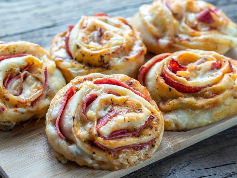 Side view of Five Pepperoni Pizza Crescent Rolls on a wooden board.