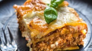 A crescent roll recipe of a single lasagna serving served on black plate.