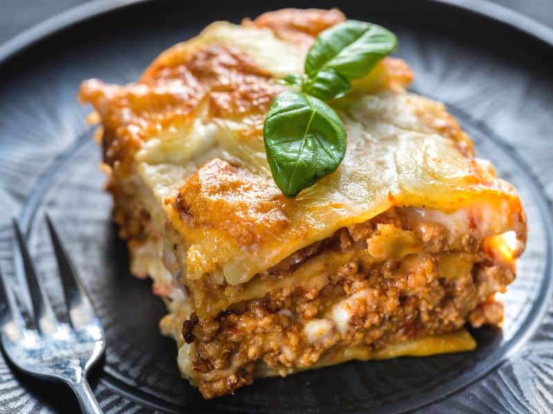 A crescent roll recipe of a single lasagna serving served on black plate.