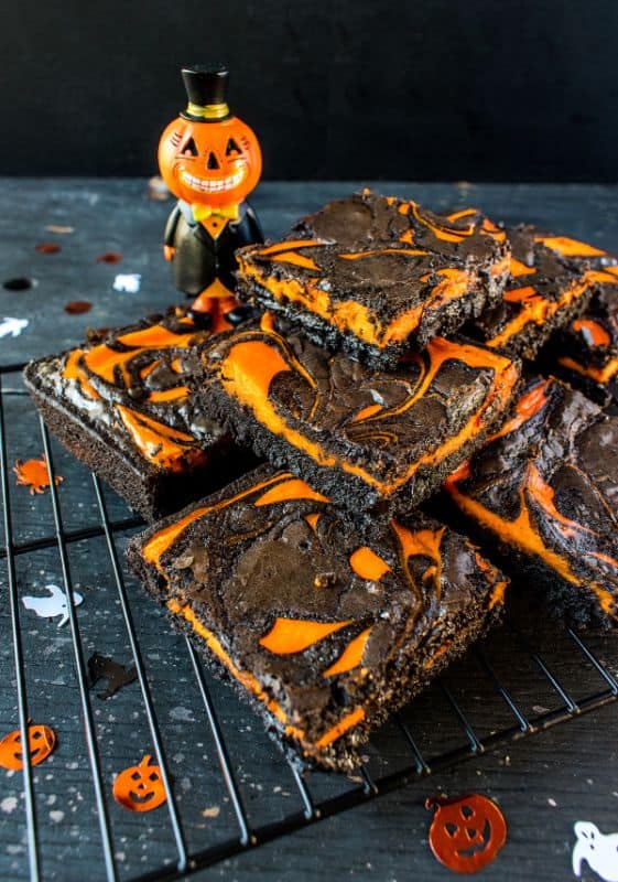 Stack of halloween brownies with orange swirls and halloween decorations.