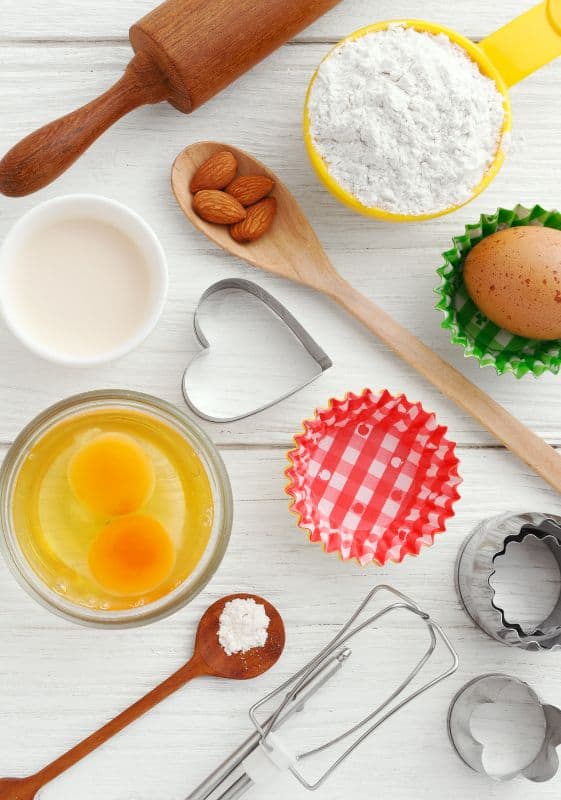 Baking ingredients with almond and eggs on a white wooden background.