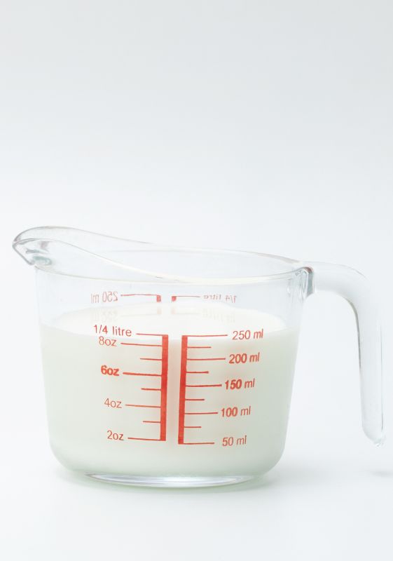 Milk in a glass measuring cup with liters and milliliters.