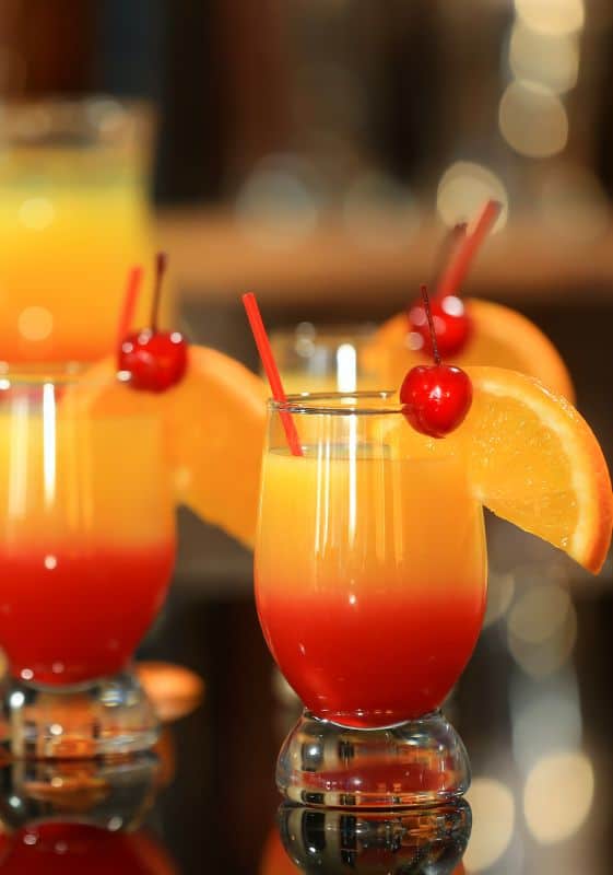 Tequila sunrise cocktails with cherries on a dark background