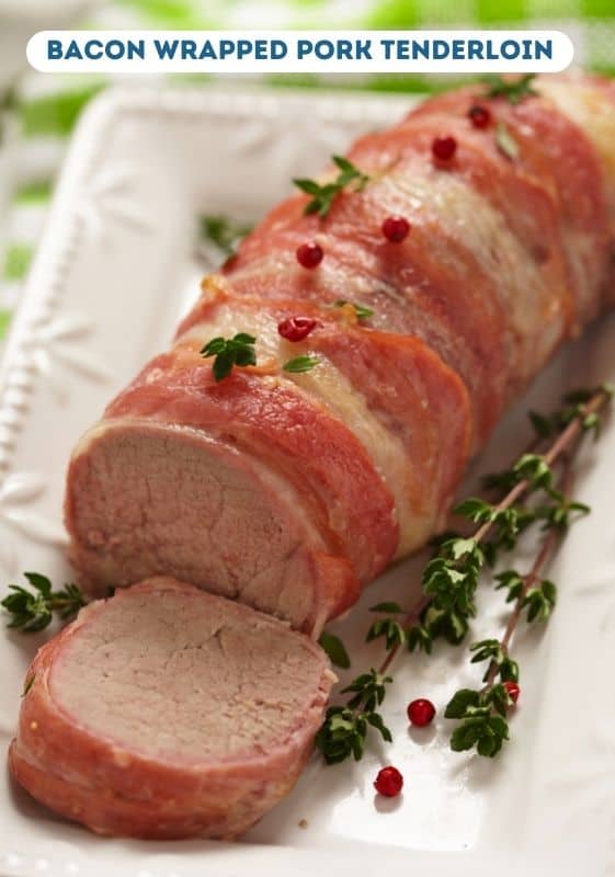 Bacon wrapped pork tenderloin on a white serving platter.