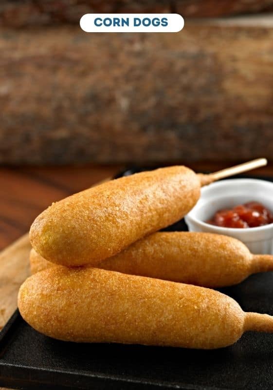 Corn dogs with ketchup on the side.