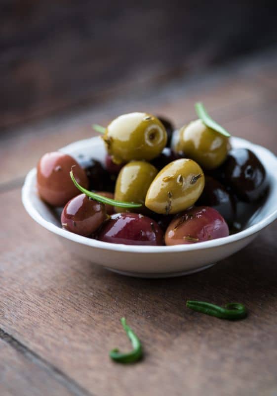 Whole olives on a white bowl.