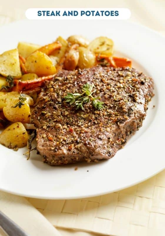 Steak and potatoes served on a white plate.