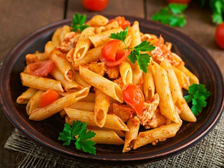 Top photo view of a brown plate with tomato chicken pasta.