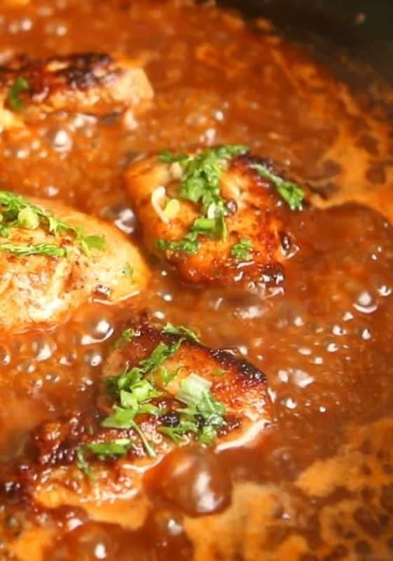 Chicken breast pieces simmering in tomato sauce.
