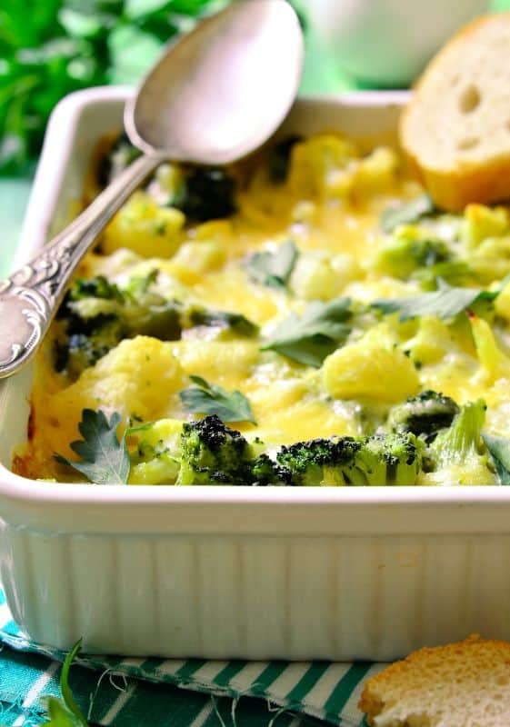 Overhead shot of a broccoli casserole garnished with extra cheese, featuring vibrant green broccoli florets peeking through the creamy, cheesy topping.