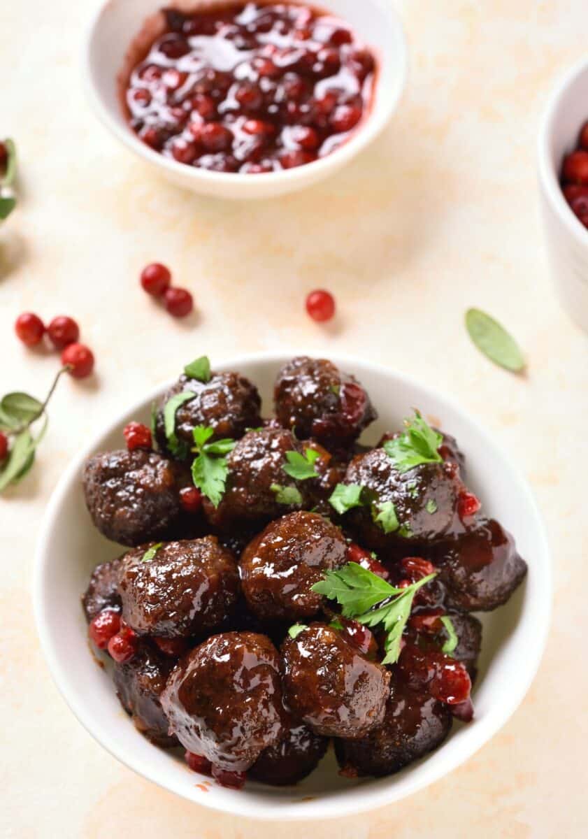 Image of meatballs on a serving platter: A platter of meatballs topped with cranberry BBQ sauce and garnished with fresh parsley.