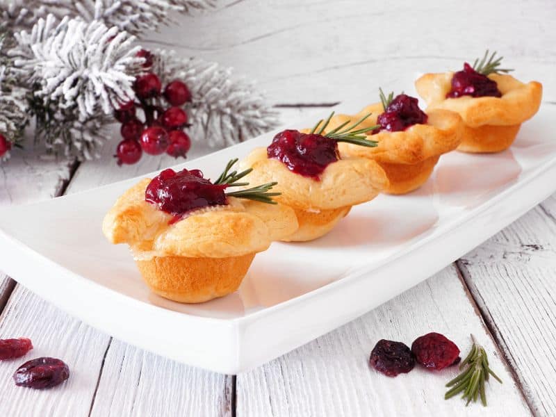 Photo side view of Cranberry brie bites in a white rectangular serving platter.