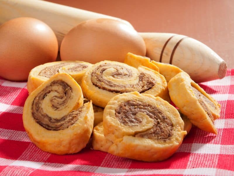 Image of a plate of sausage pinwheels. The pinwheels are made with crescent rolls, sausage, cream cheese, and green onions. They are baked until golden brown and served warm.