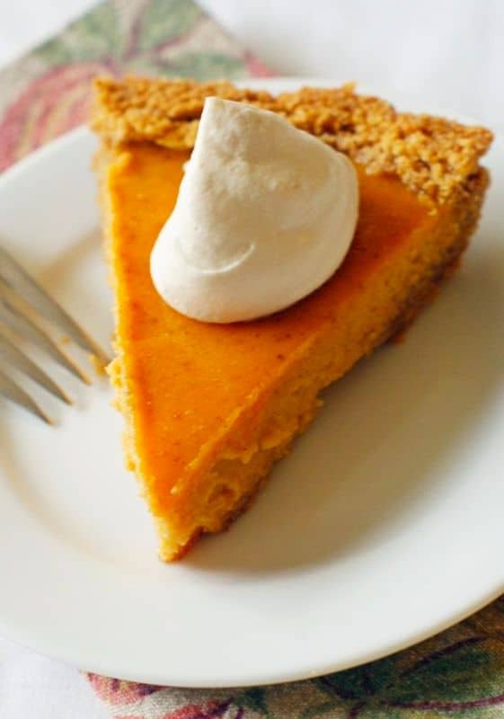 Photo of a slice of sweet potato pie topped with whipped cream.