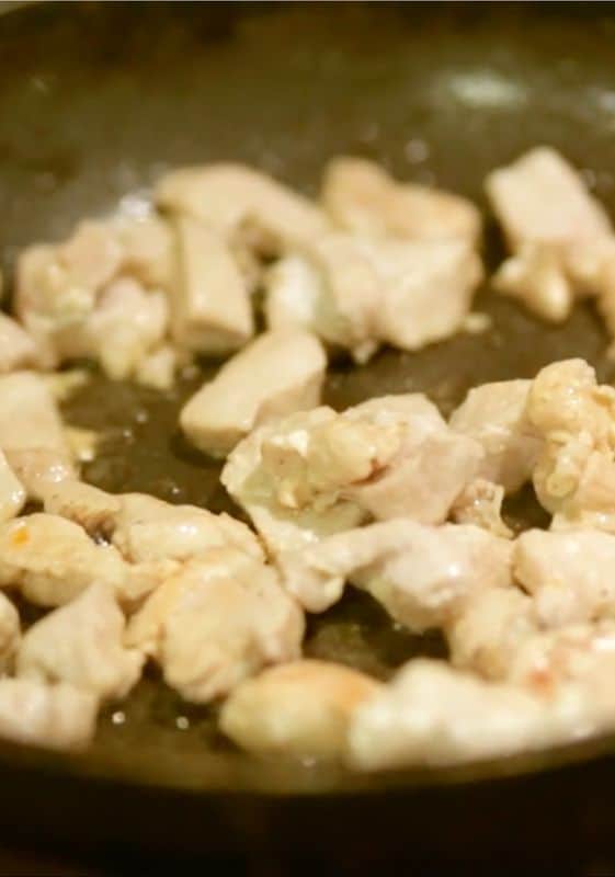 Chicken breast pieces cooking in frying pan.