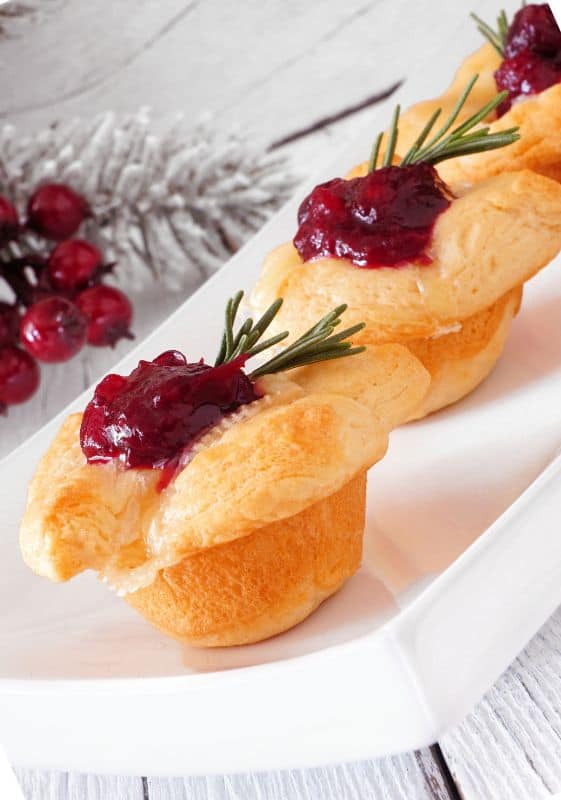 Image of Garnished Cranberry Brie Bites: Beautifully garnished Cranberry Brie Bites with fresh rosemary leaves, adding a festive touch to these delightful bite-sized appetizers.