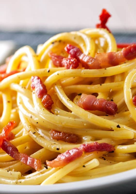 A delightful and creamy pasta dish topped with crispy bacon lardons and a touch of black pepper.