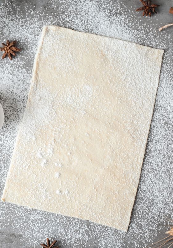 Image of Preparing the Puff Pastry: Step-by-step guide to preparing the puff pastry for Cranberry Brie Bites: rolling out the thawed pastry sheet on a floured surface.