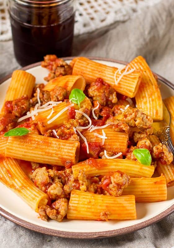 A close-up of the Rigatoni pasta coated in Bolognese sauce, emphasizing the glossy, flavorful coating.