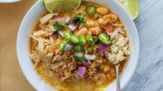 A homemade white bean chicken chili garnished with grated cheese and sliced jalapenos.