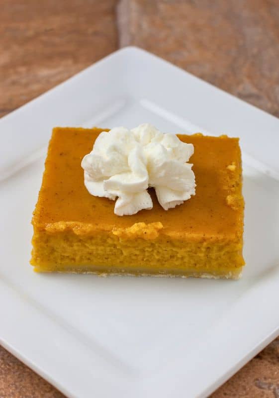 Top view of a Healthy Pumpkin Pie Bar with whipped cream on a white plate.