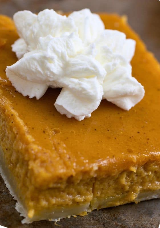 Close-up view of a Healthy Pumpkin Pie Bar with whipped cream on top.
