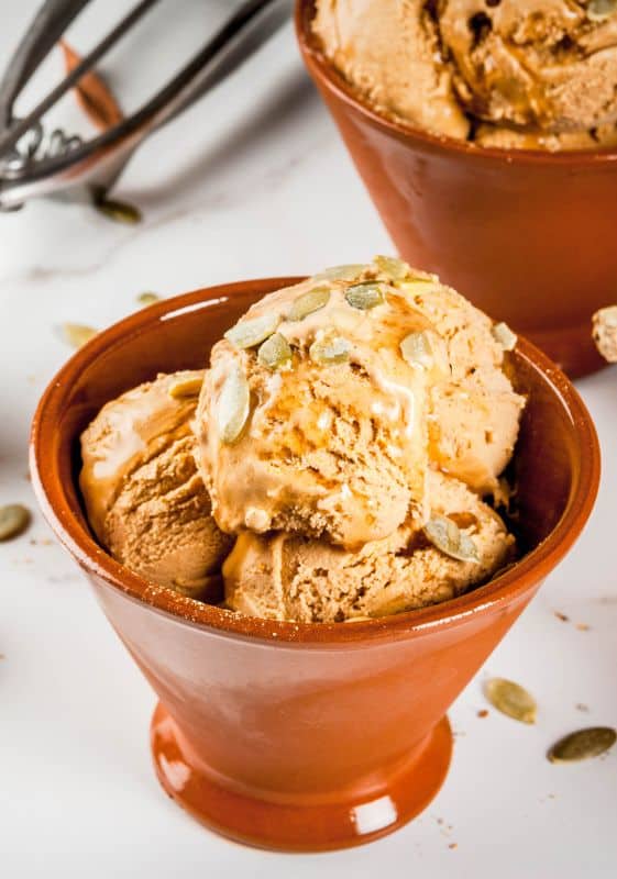 Pumpkin pie ice cream served on a terracotta cup on a white table. Healthy Thanksgiving desserts.